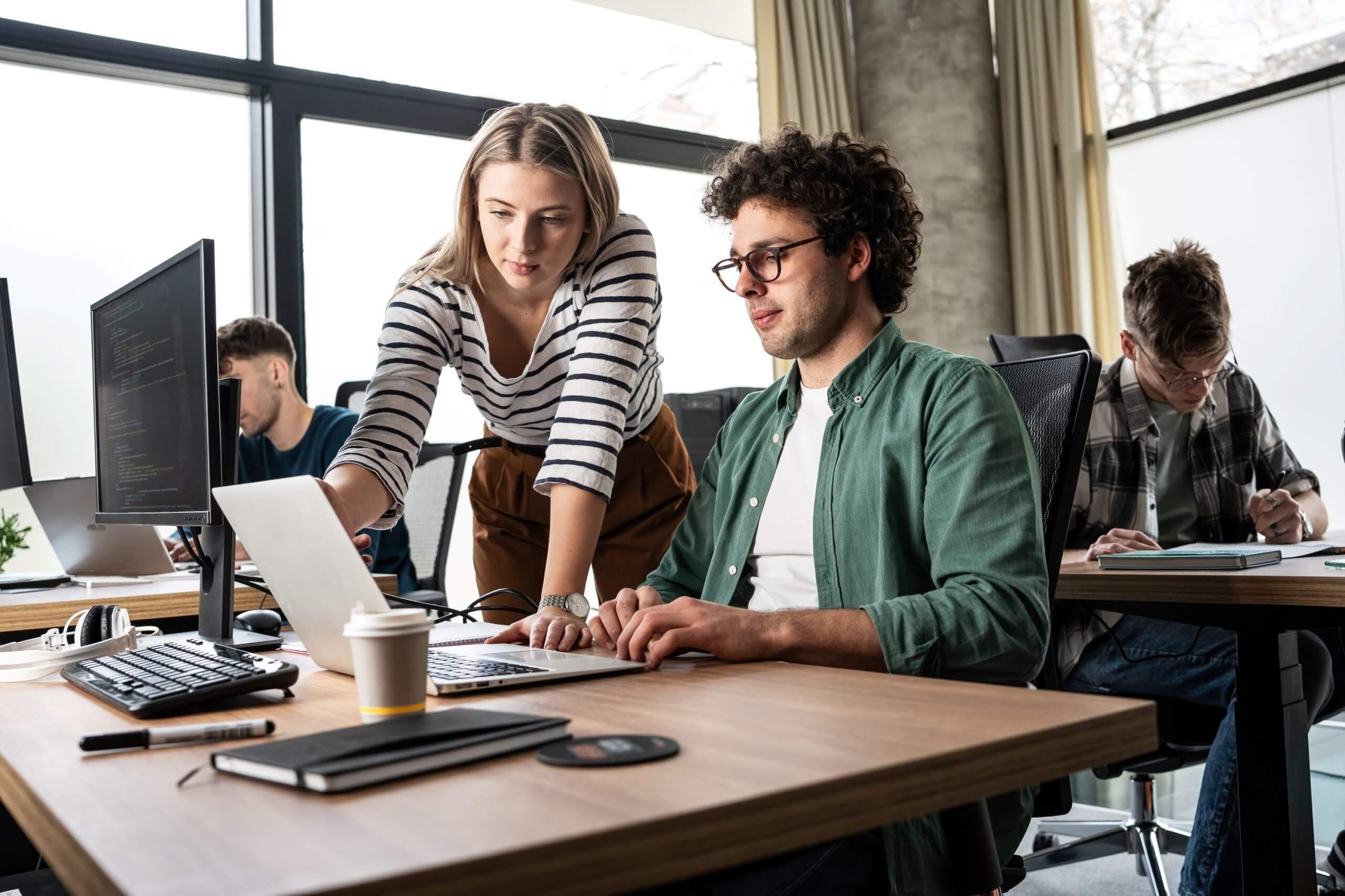 Mitarbeitende schauen gemeinsam auf einen Computer im Büro